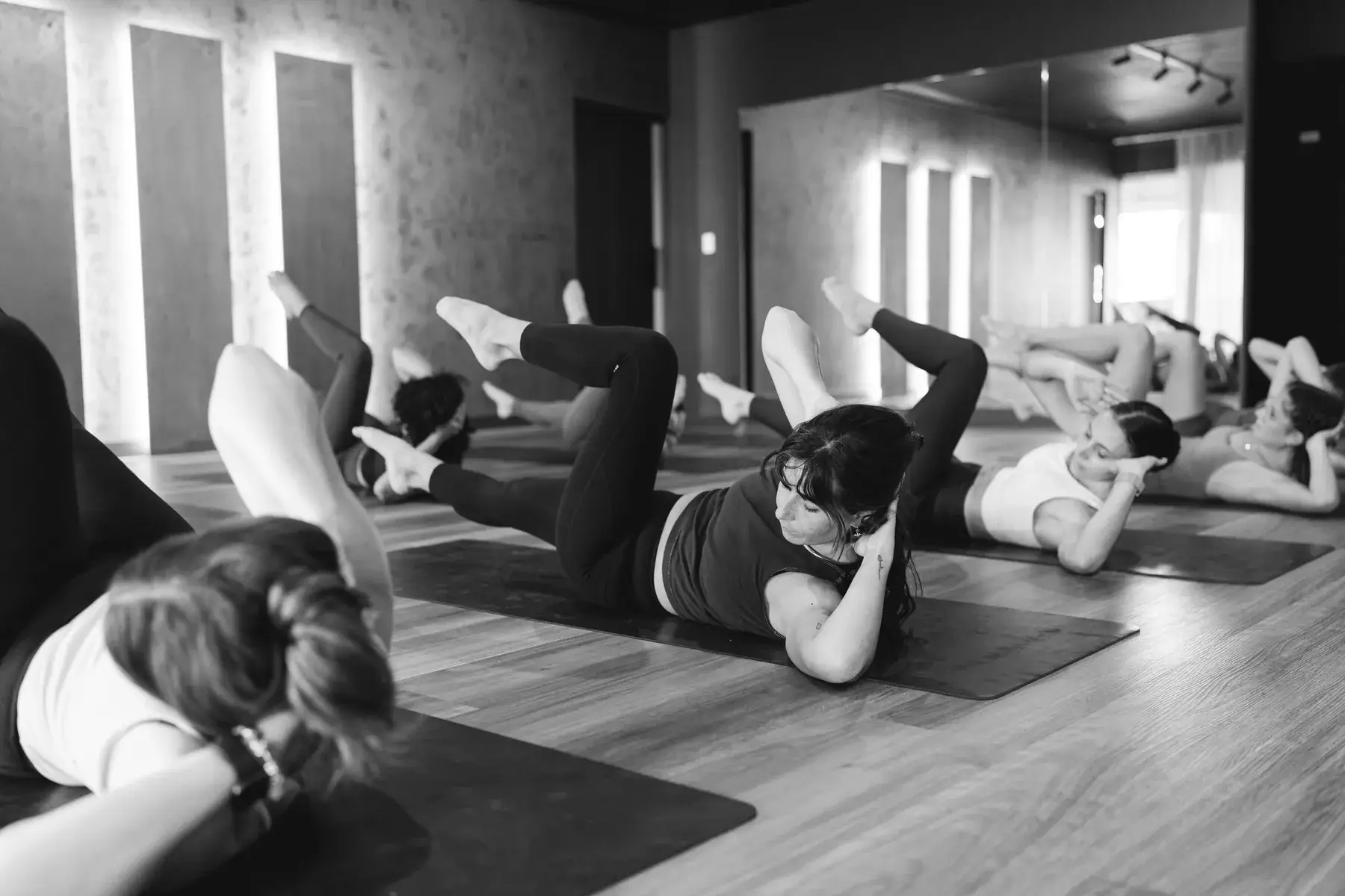 Black and white photo of a full class lying on their mats doing floor work together