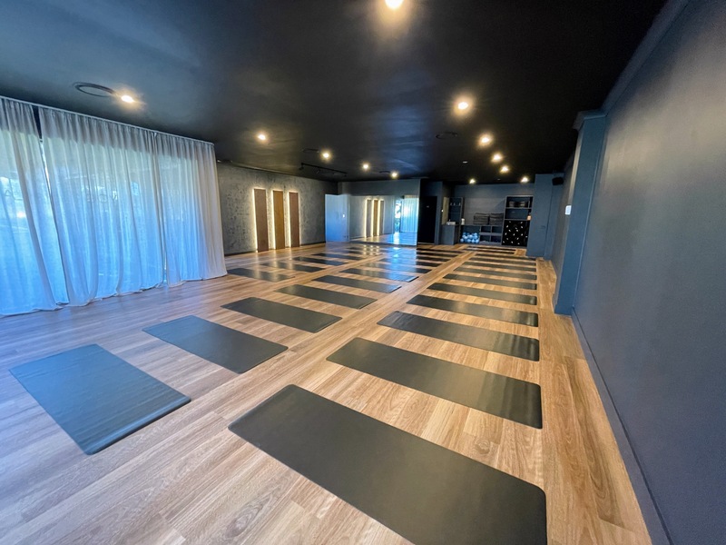 Inside the Flolo Robina studio, warm timber floors, dark walls and mats laid out